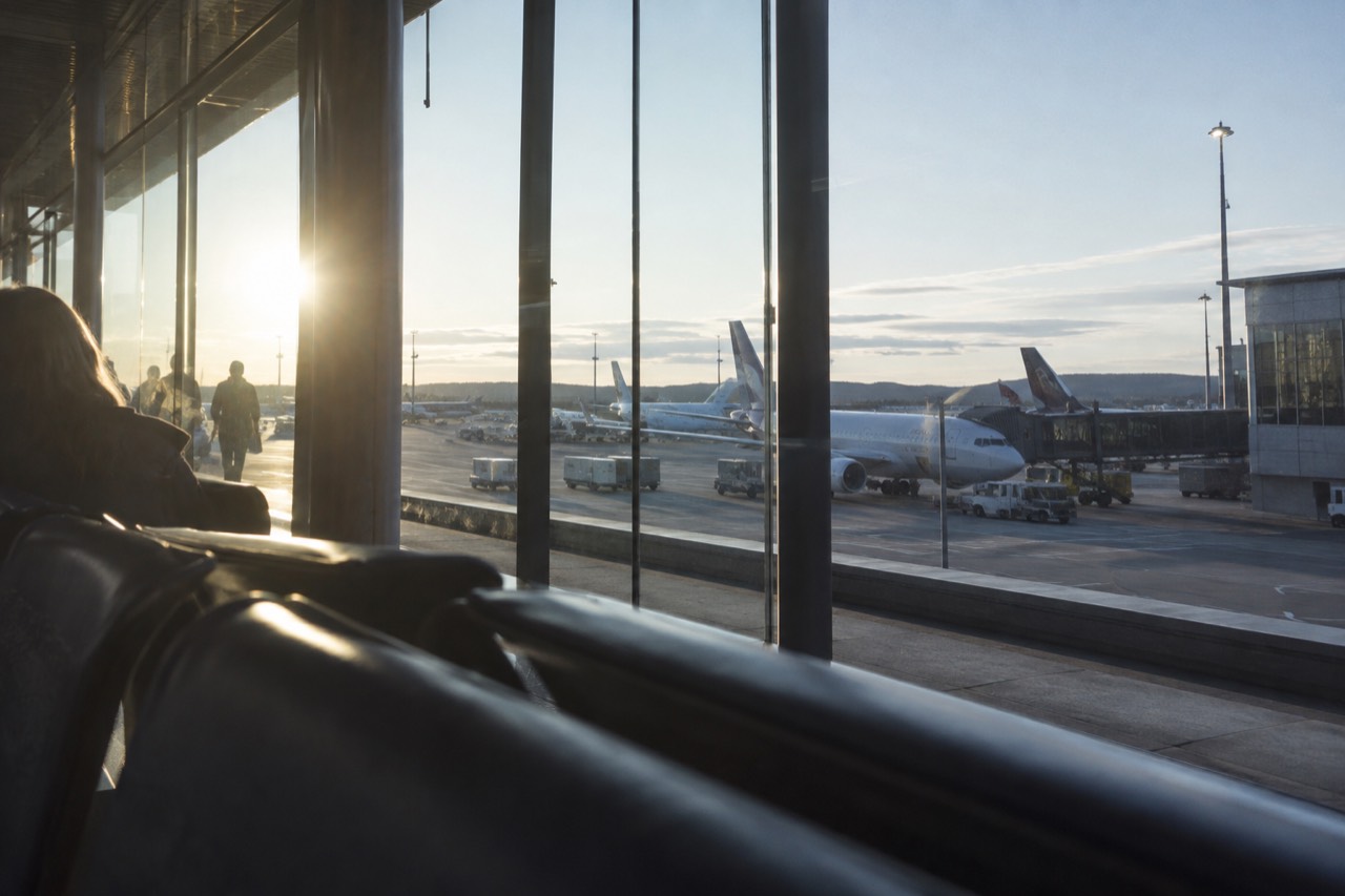 Airport terminal building with aircraft parked at gates under a pale Nordic sky