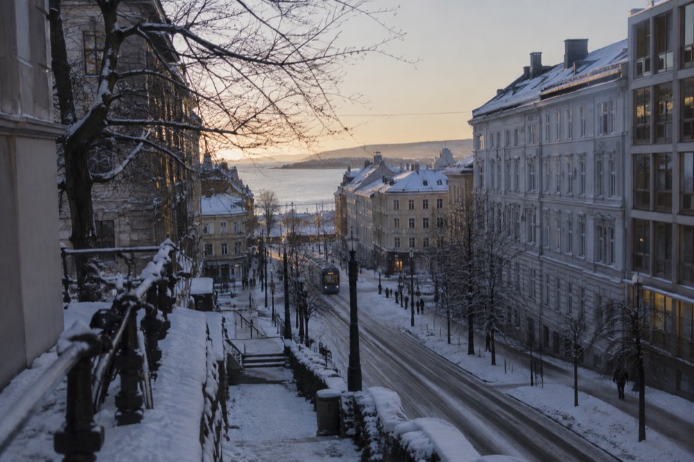 Snow-covered street with parked bicycles and bare trees in an Oslo winter