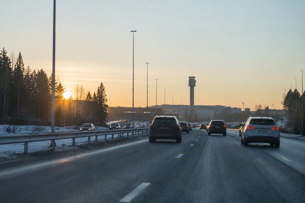 Cars moving along a highway toward the Oslo skyline in late afternoon light