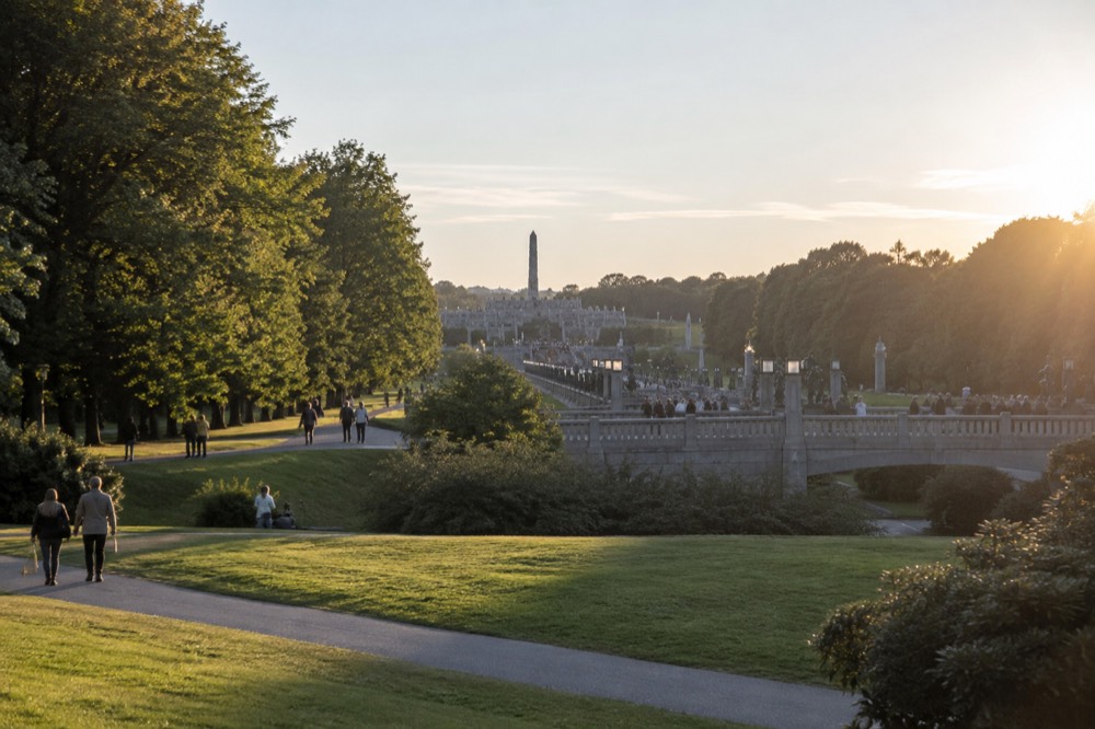 Visitors strolling the tree-lined lawns of Vigeland Park in soft daylight