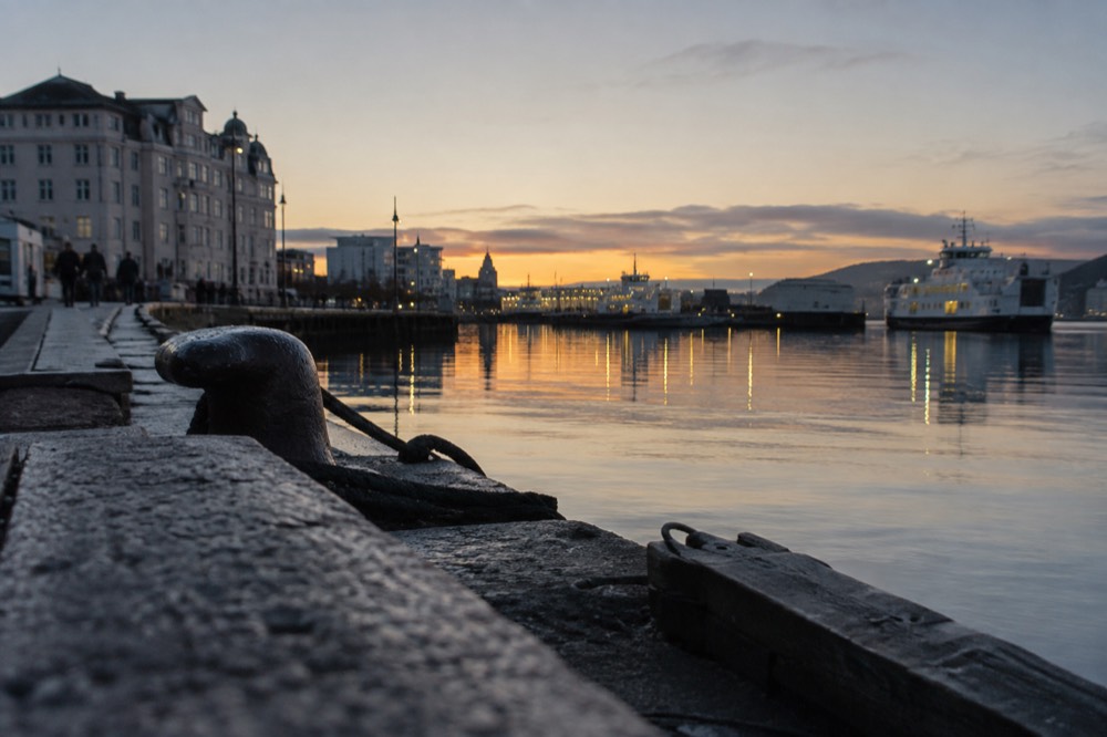 Oslo harbor at dusk with ferry lights reflected in still water