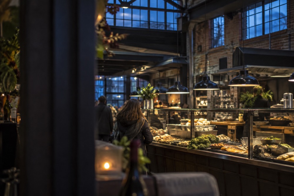 A food hall counter with trays of Norwegian dishes under warm lights