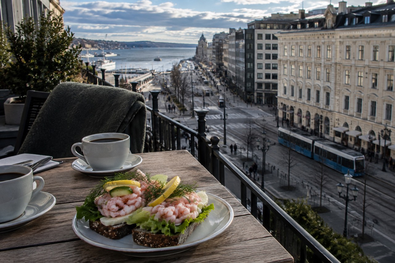 Open-faced shrimp sandwiches and coffee on a wooden cafe table in Oslo