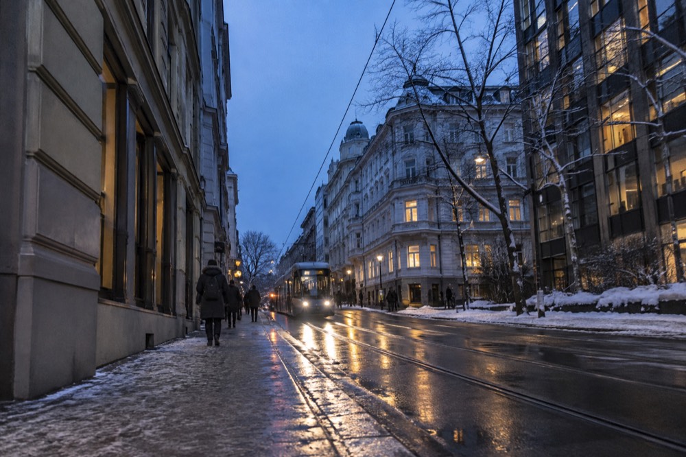 Oslo city street in winter with snow on rooftops and lights reflecting on the pavement