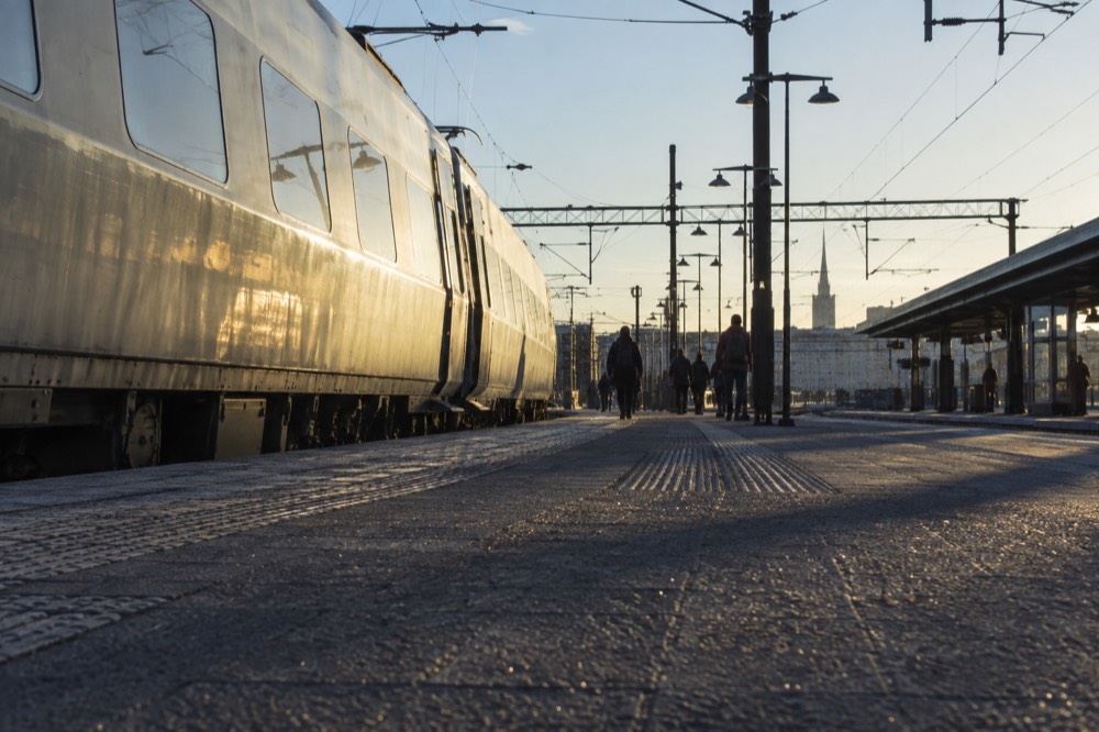 A passenger train waiting at a Scandinavian station platform under a pale sky