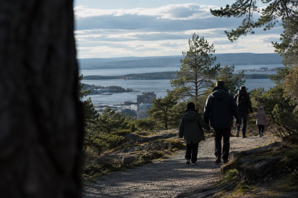 Families walking a gravel path through pine forest above the Oslofjord