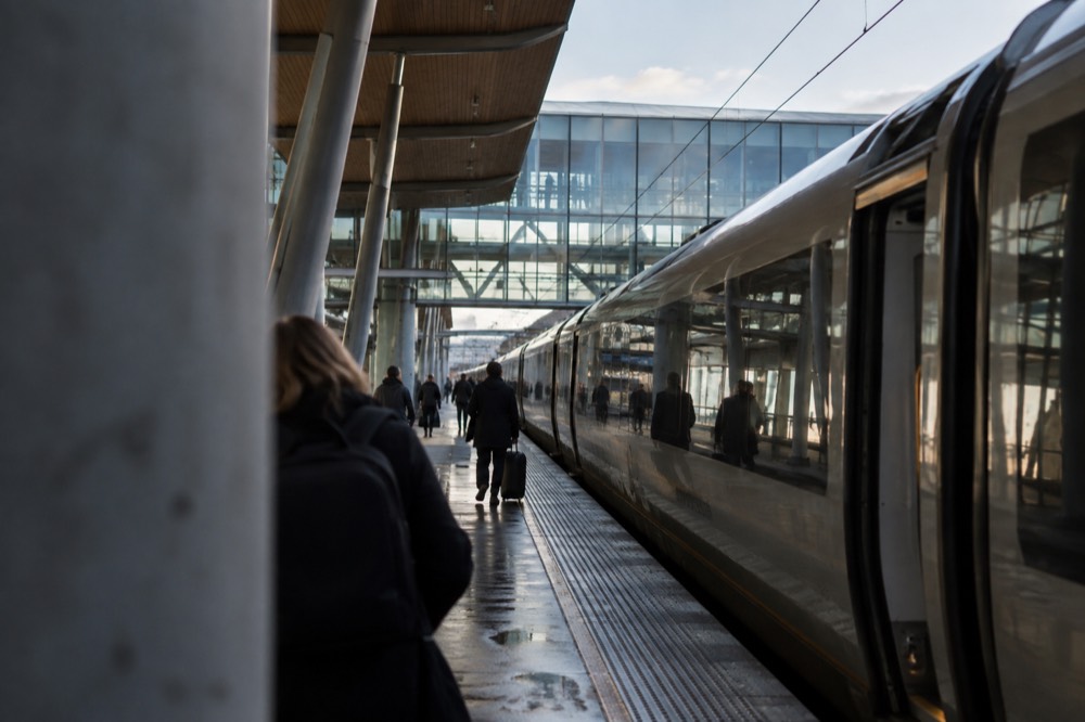 Airport express train waiting at a platform beside a modern glass station facade