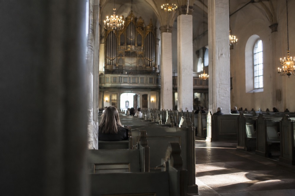 Interior of Oslo Cathedral with tall columns, pews and the organ above the entrance