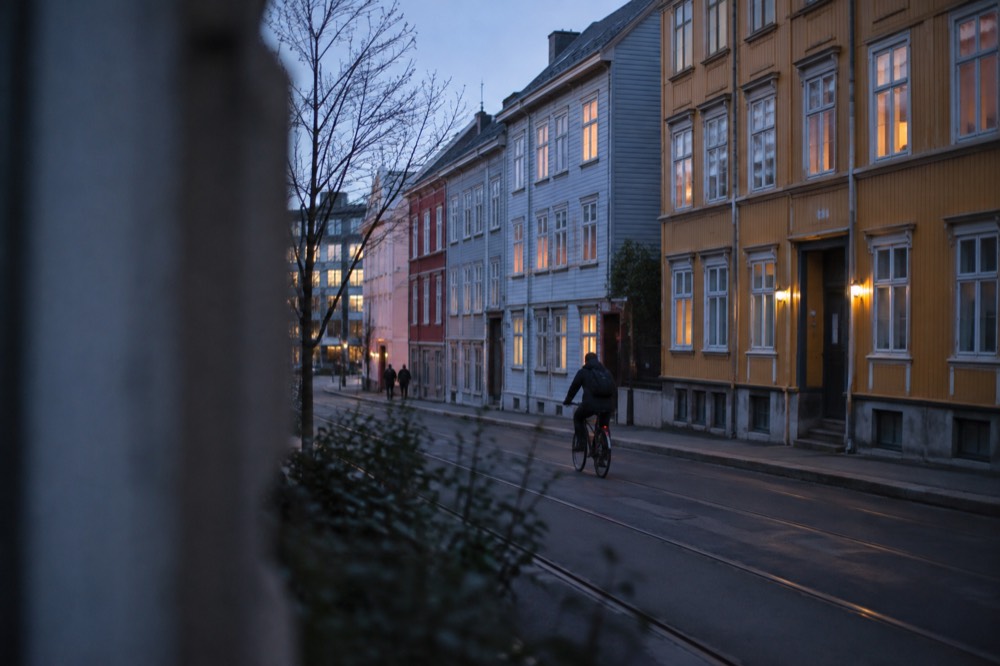 Colorful wooden apartment buildings in central Oslo with a cyclist on the street