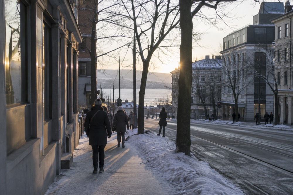 People walking through an illuminated Oslo city street after dark in winter