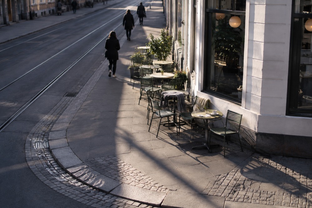 A quiet street corner with café tables and chairs outside a small coffee shop in Grünerløkka