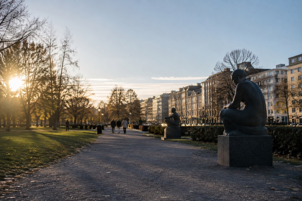 Sculptures along a gravel path in a large open park with trees