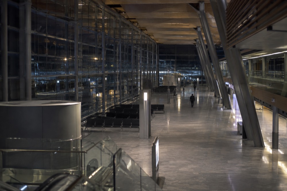 An empty airport terminal concourse at night with departure boards glowing