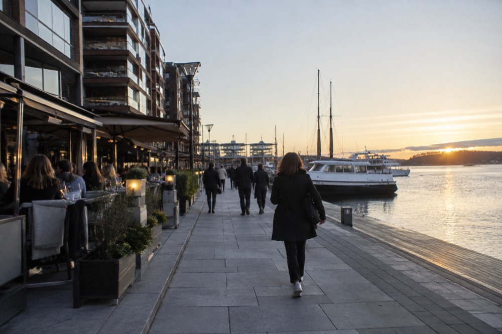 Aker Brygge waterfront promenade in evening light with diners outside