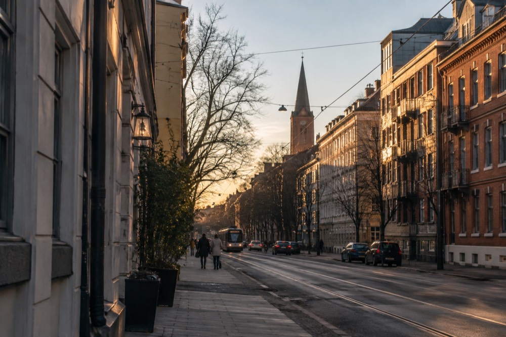 Row of brick apartment buildings and a church tower in a residential Oslo district