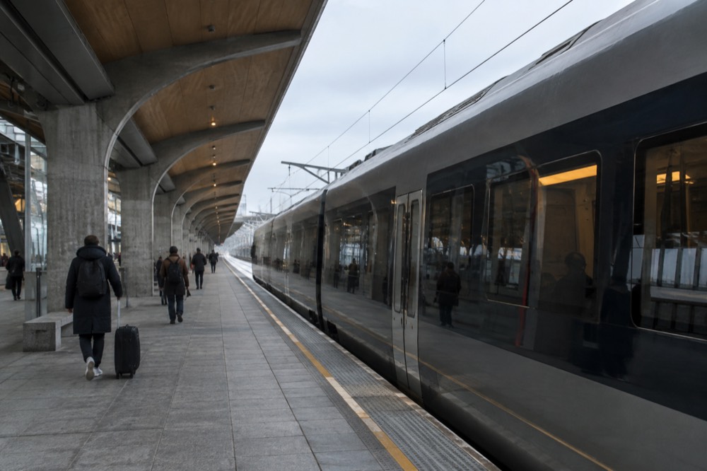 A modern airport express train at a platform inside Oslo Airport Gardermoen