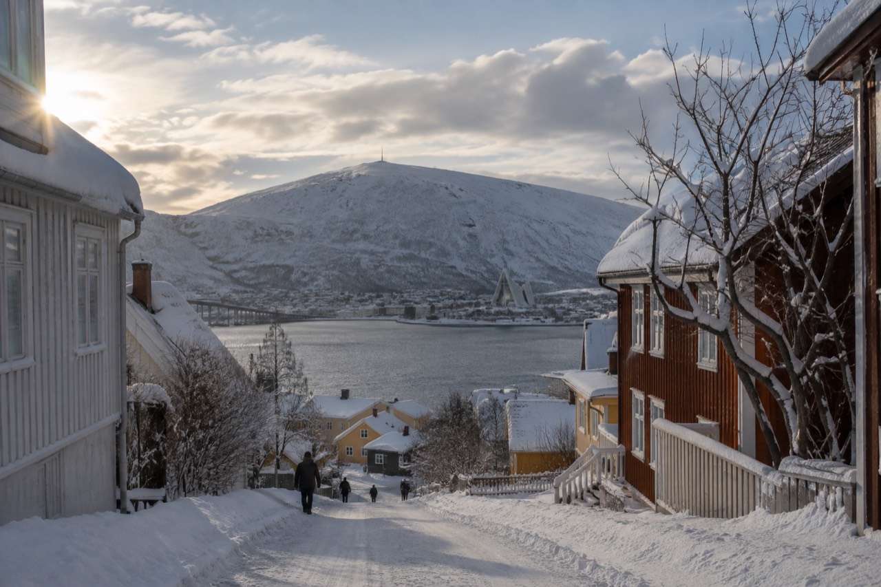 Winter street scene in Tromsø with snow-covered wooden houses and a hilltop church