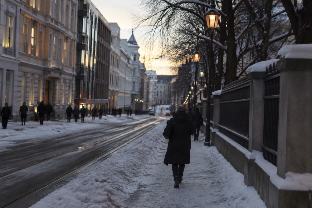 Winter street in central Oslo lit by lamps in the late afternoon dark