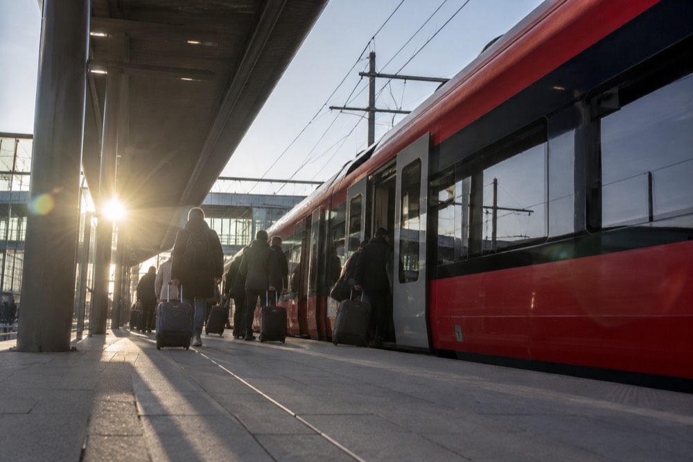 A red airport express train waiting at a station platform with passengers boarding