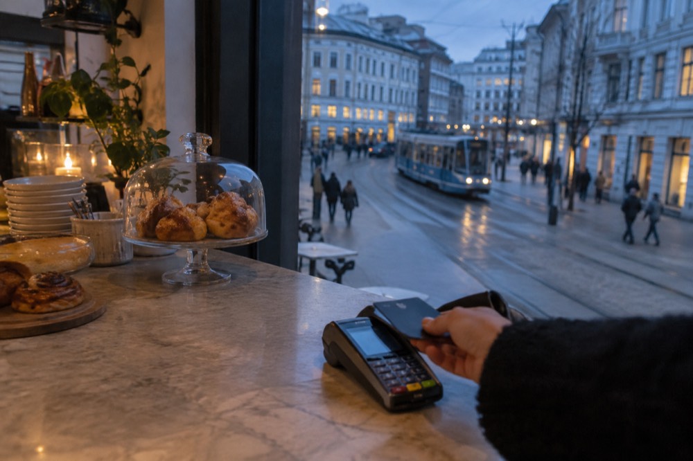 A handheld card terminal on a cafe counter next to a receipt