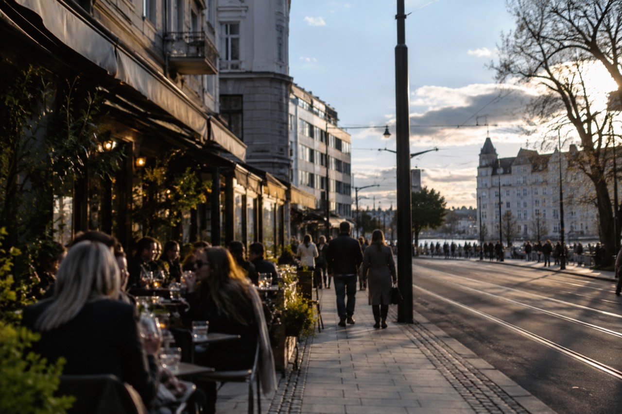 Evening light over restaurant terraces along a busy Oslo street