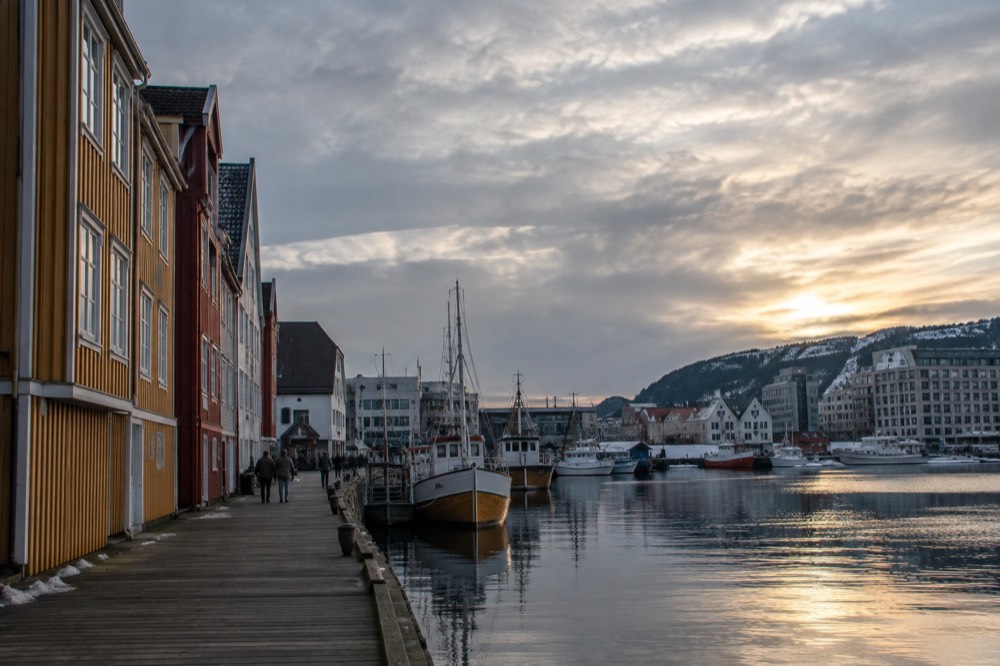 Wooden houses and a harbor in a Norwegian coastal town under an overcast sky