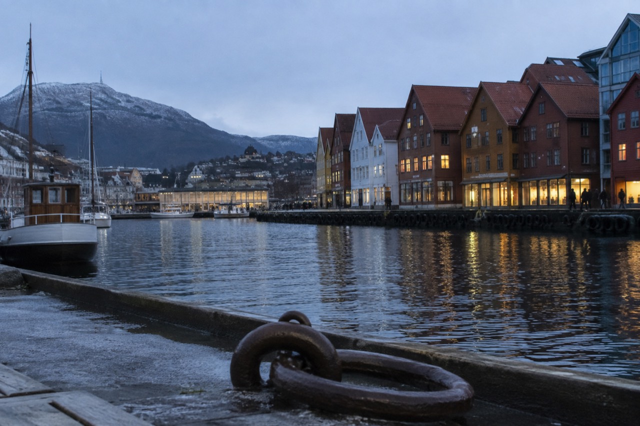 Colorful wooden buildings along a Norwegian waterfront with mountains behind