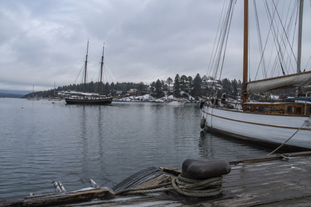 Wooden sailing ships moored on the Oslofjord with the Bygdøy peninsula shoreline behind them