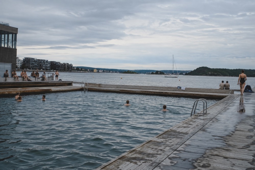 Seawater swimming pool at Sørenga with people in the water and the fjord beyond