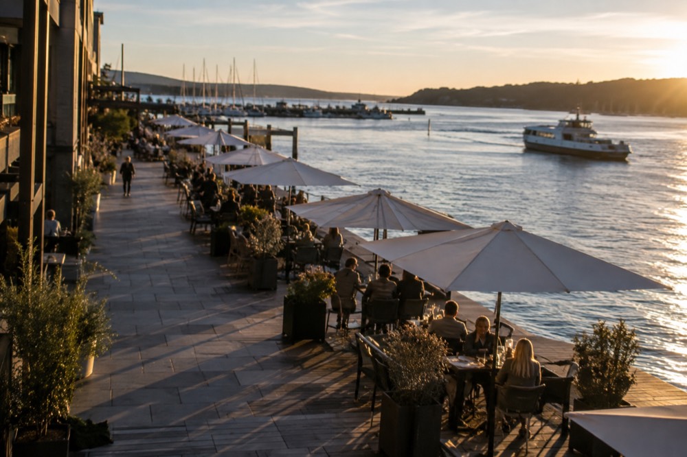 Outdoor restaurant tables along the waterfront promenade in evening light