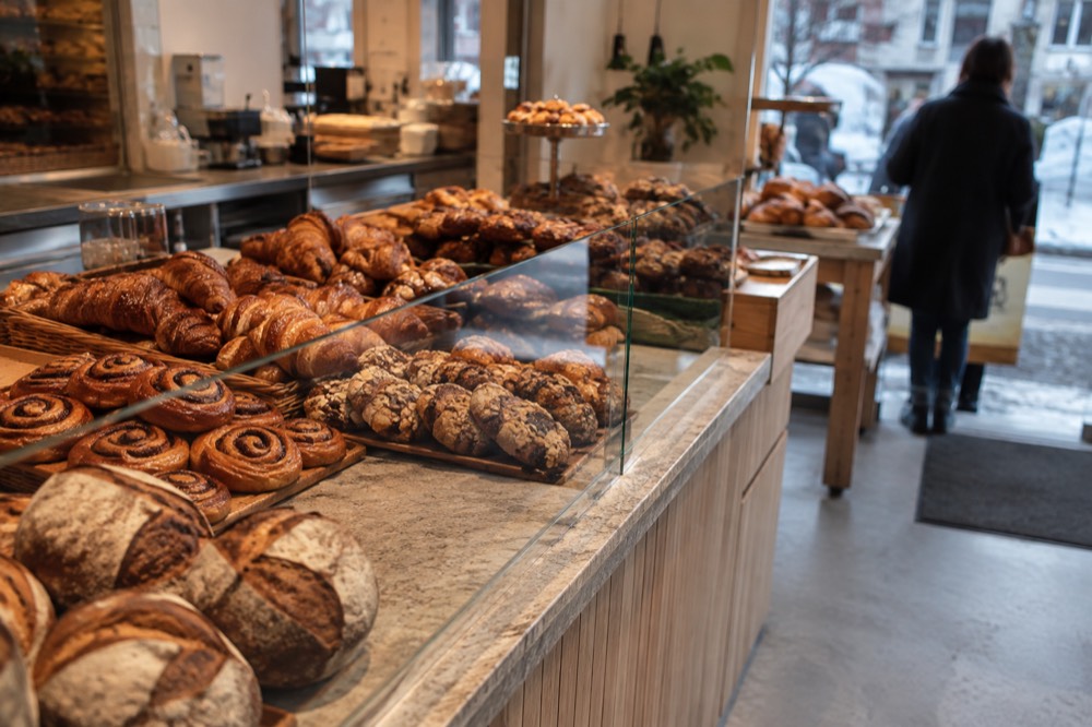 A counter of pastries and bread in a bright bakery interior