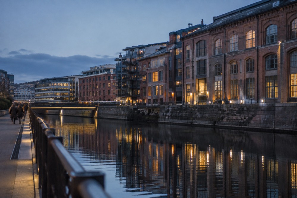 Old industrial brick buildings reflected in a calm river at dusk