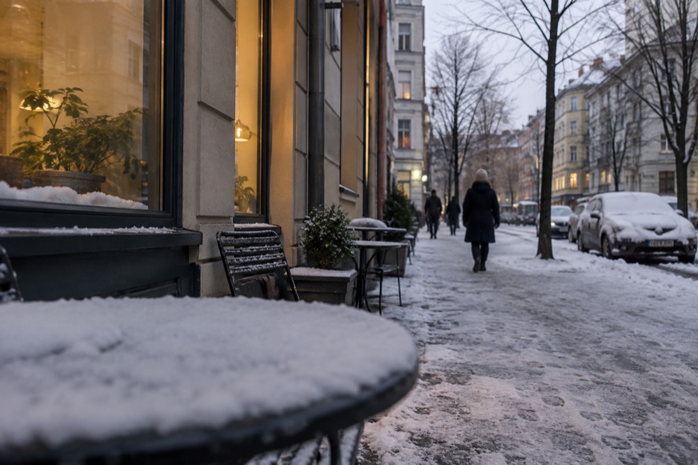Snow-dusted street corner with warm light from shop windows in winter