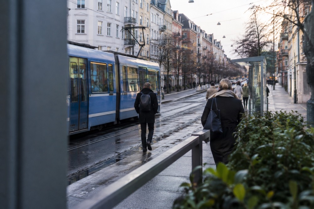 Tram tracks and platform at a busy Oslo street junction with apartment buildings behind