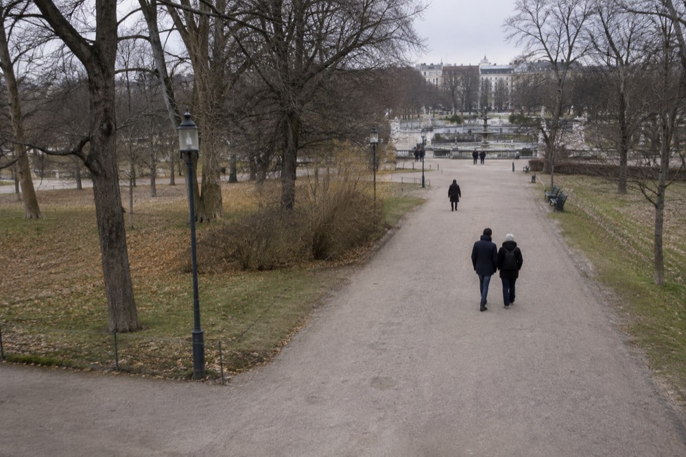 Wide gravel path through a large city park with sculptures visible in the distance