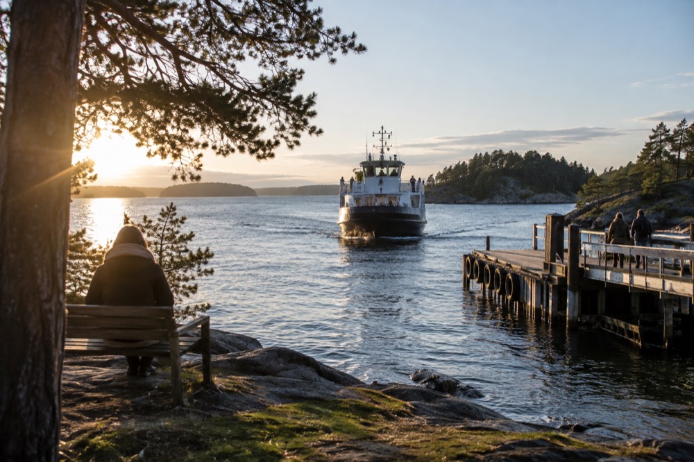 Passenger ferry approaching a small wooded island pier in the Oslofjord