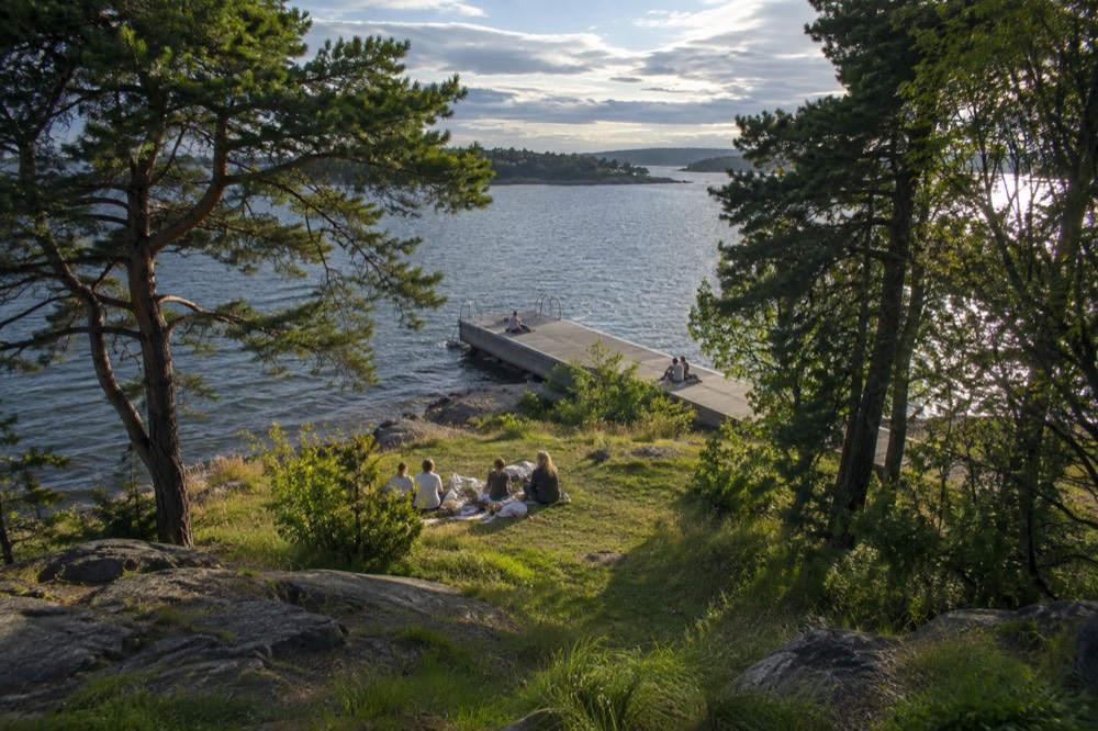 People picnicking on grass beside a small island pier in summer