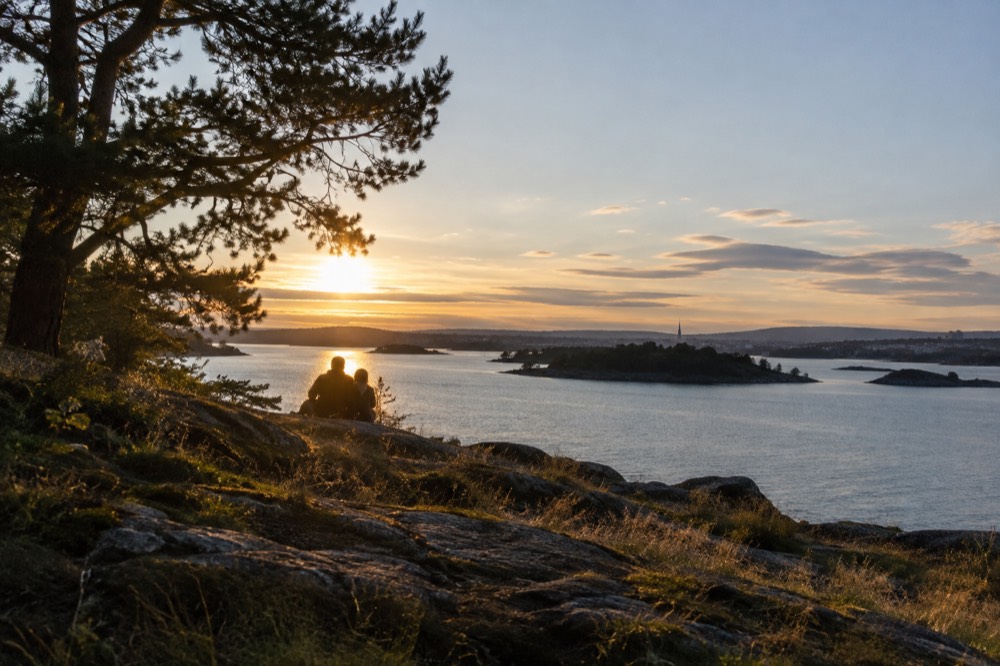 Evening light over calm fjord water with islands and city skyline beyond