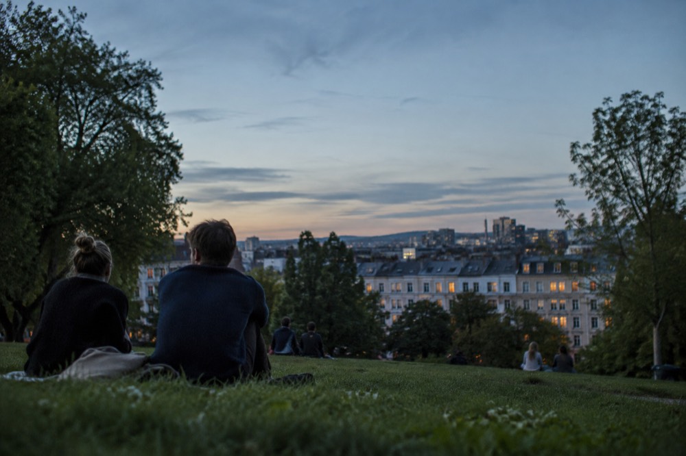 A park lawn in evening light with long shadows and the city skyline beyond