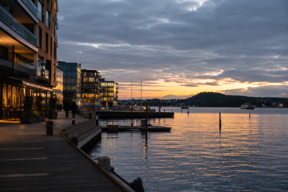 Waterfront promenade at dusk with city lights reflecting in the Oslofjord