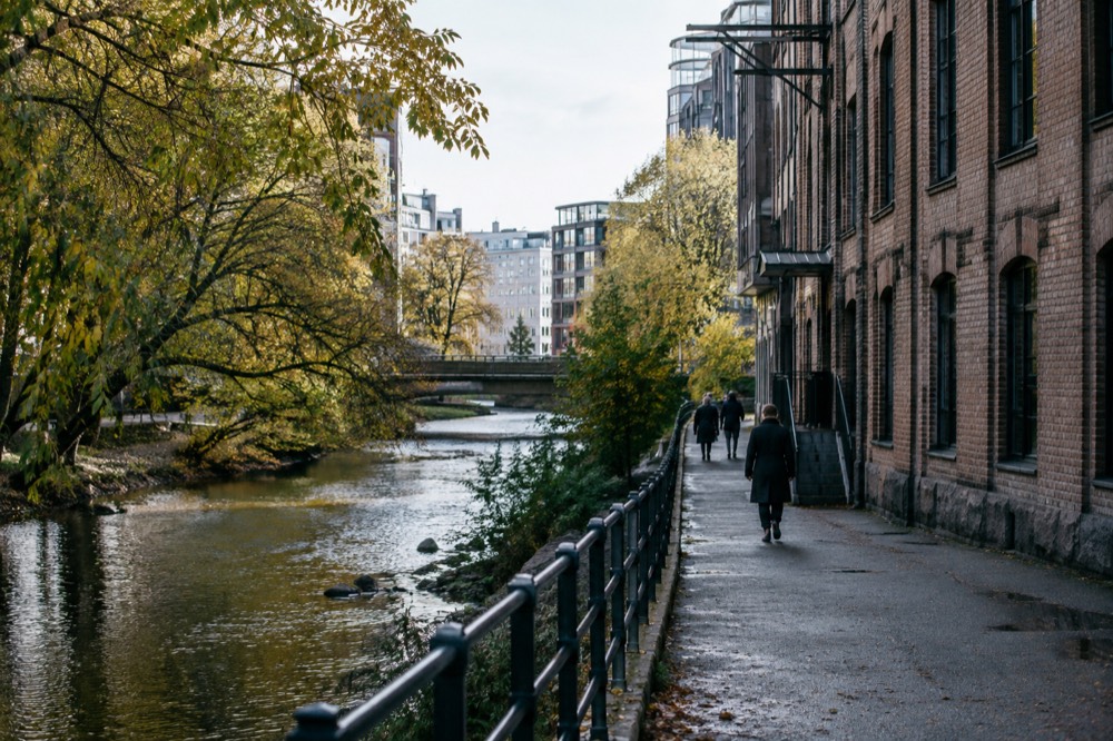 River path beside an old brick factory building with trees overhanging the water