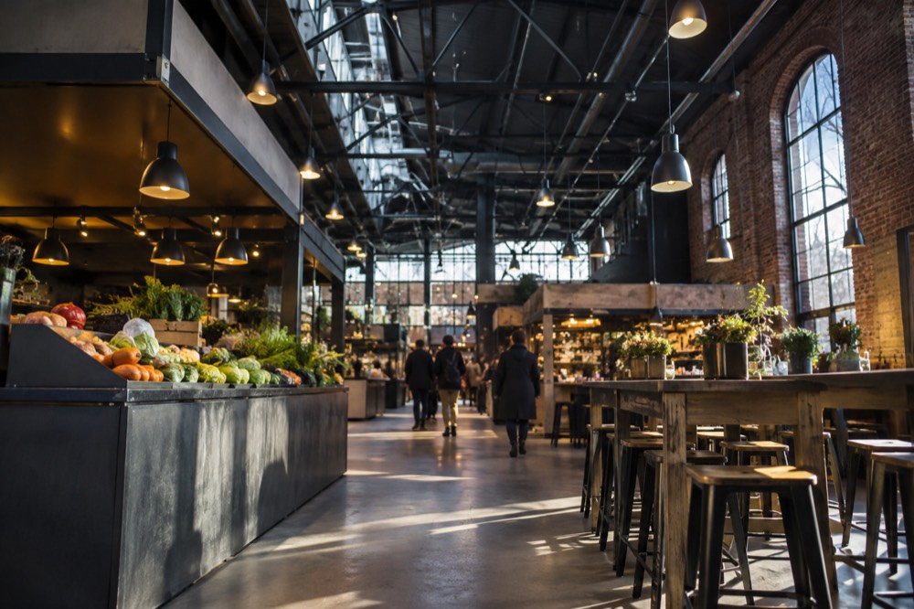 A food hall interior with high ceilings, stall counters and communal wooden tables