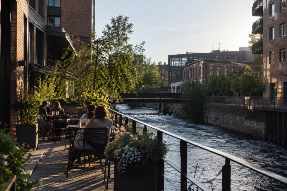A riverside terrace with tables and chairs beside a river under an evening sky
