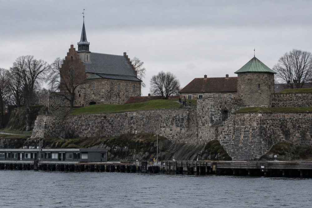 Stone fortress walls and green ramparts above the Oslofjord waterfront in Oslo