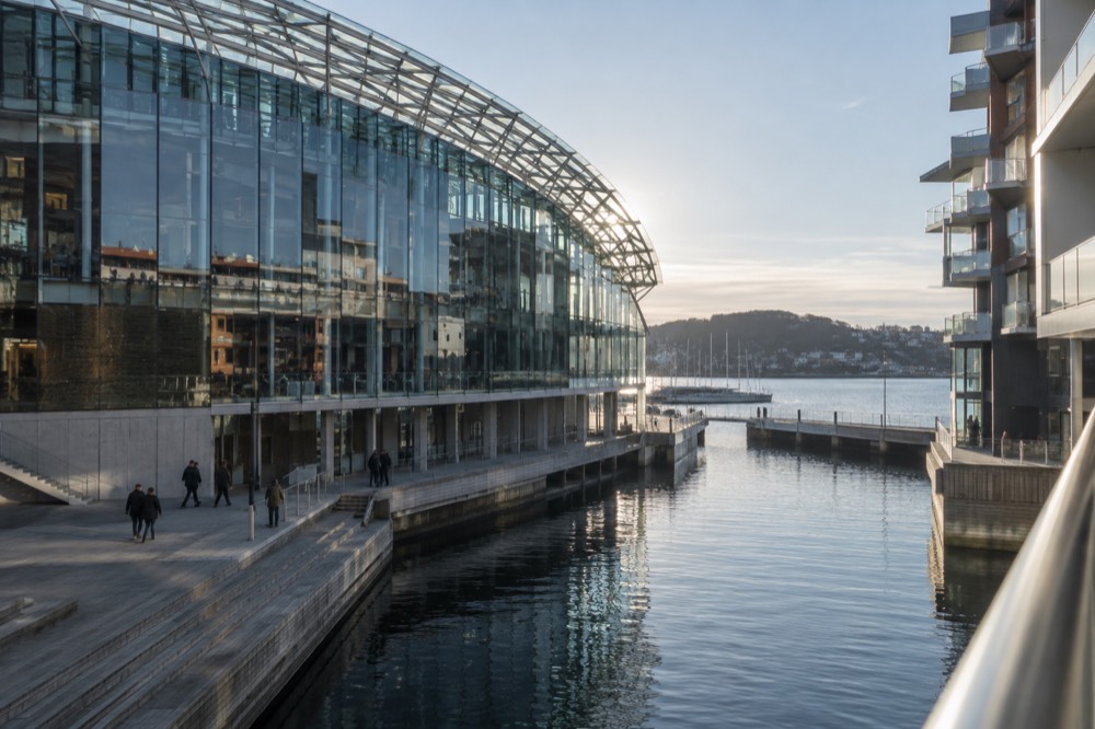 Glass museum building with a curved roof beside a narrow canal