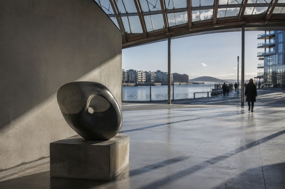 Sculpture displayed in a gallery corner with natural light from skylights