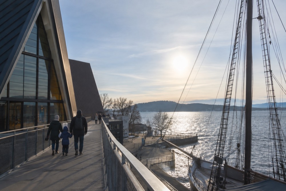A family walks the upper walkway beside the ship's tall rigging at the Fram Museum