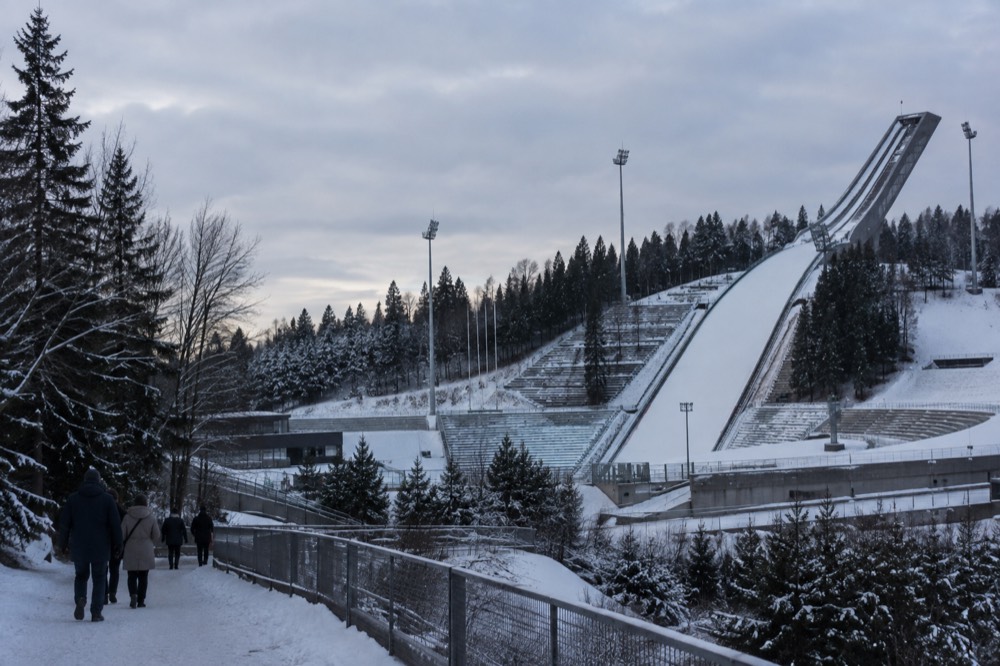 The ski jump arena at Holmenkollen under snow with the stands and jump tower in winter light