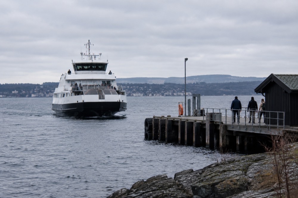 White passenger ferry approaching a small island pier on blue water