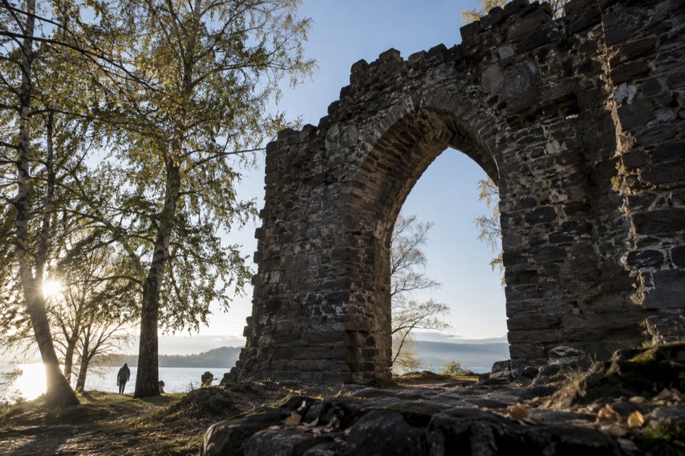 Weathered stone archway of a ruined monastery framed by birch trees
